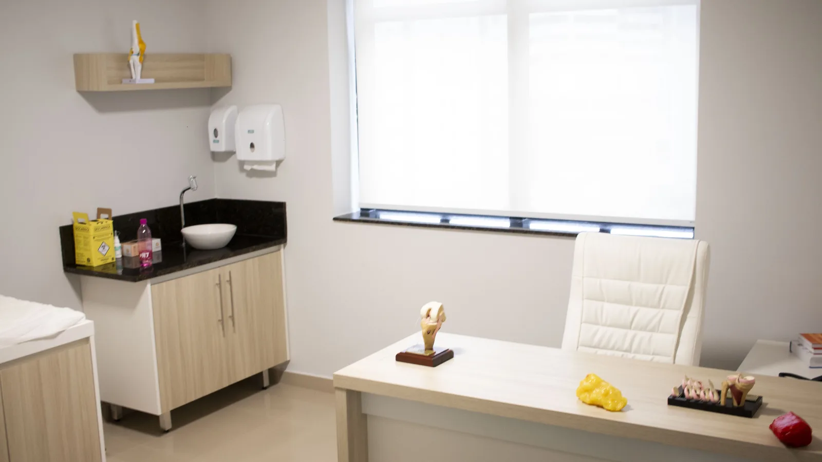 Consultório de Edson Santiago no Jardim Paulista, com mesa de avaliação e modelos anatômicos